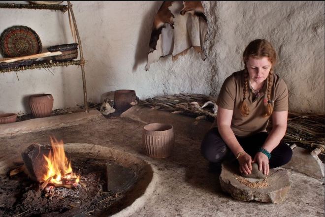 Wendy grinding corn on the first day the Neolithic Houses opened